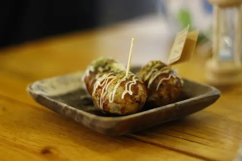 Bolitas de takoyaki cubiertas con salsa y katsuobushi